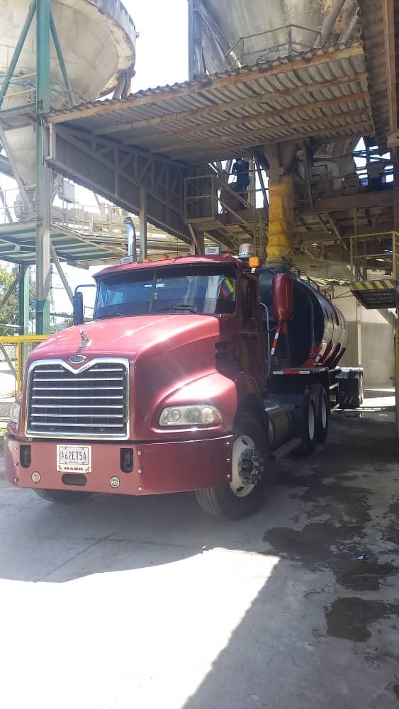 Camión cisterna cargando cemento a granel en planta